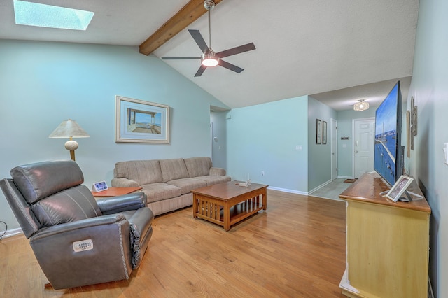 living area with a ceiling fan, light wood-style flooring, baseboards, and vaulted ceiling with skylight