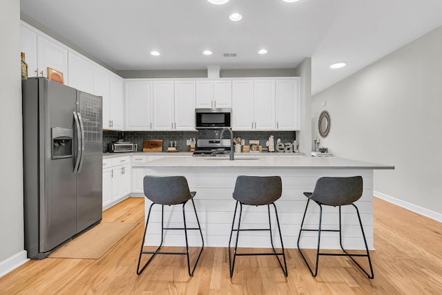 kitchen featuring white cabinets, appliances with stainless steel finishes, a breakfast bar area, and sink