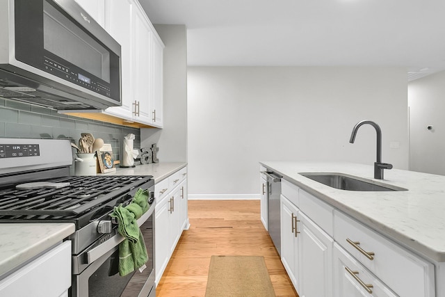 kitchen featuring white cabinets, decorative backsplash, light stone countertops, and appliances with stainless steel finishes