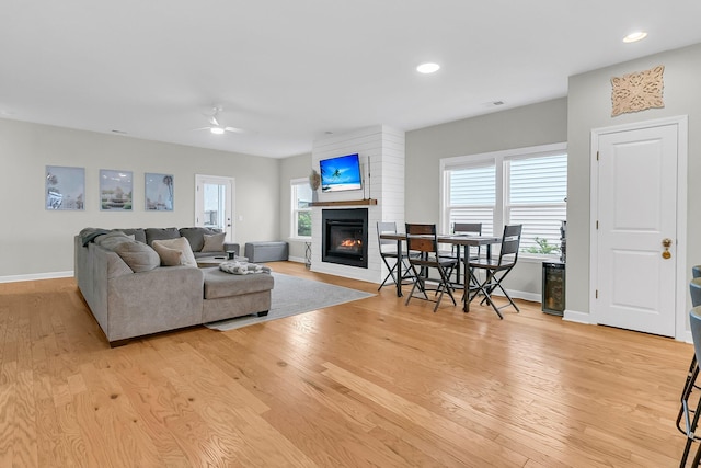 living room with ceiling fan, a wealth of natural light, and light hardwood / wood-style flooring