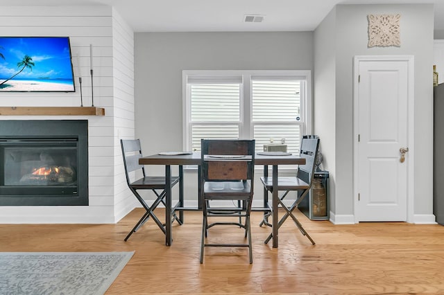 dining space featuring a large fireplace and hardwood / wood-style floors