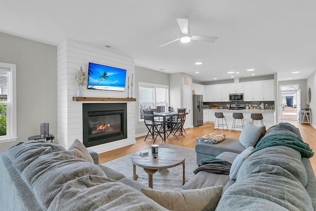 living room with a fireplace, light hardwood / wood-style flooring, and ceiling fan