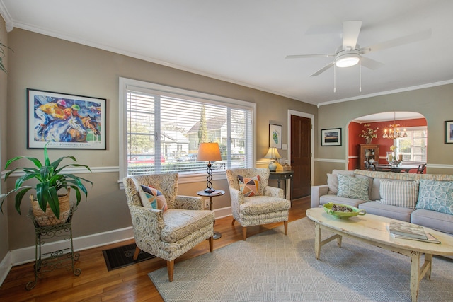 living room with arched walkways, wood finished floors, a wealth of natural light, and crown molding