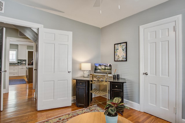 home office with visible vents, ceiling fan, baseboards, and wood finished floors