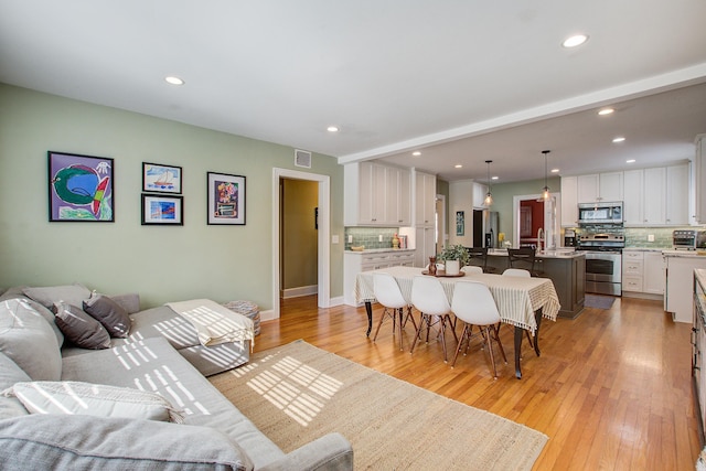 living area featuring a toaster, light wood finished floors, visible vents, and recessed lighting