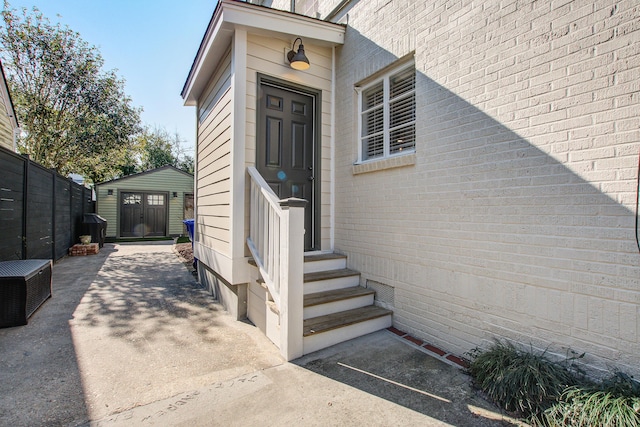 entrance to property featuring fence and brick siding