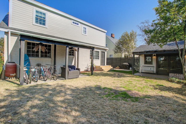 back of house with brick siding, a yard, a patio, and fence