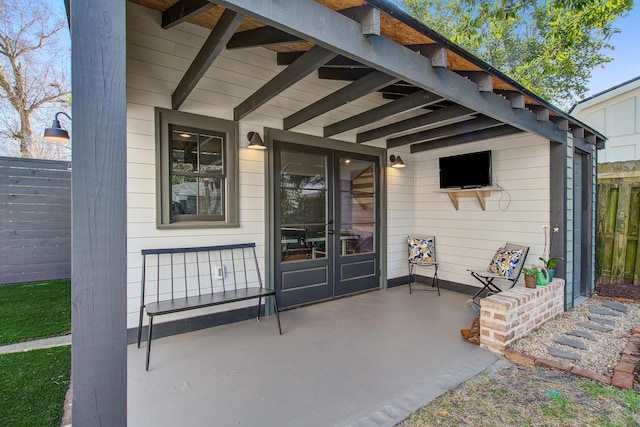 view of exterior entry featuring fence and a patio