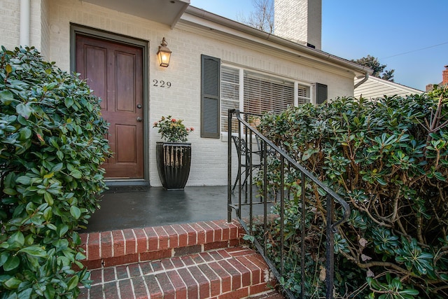 doorway to property with brick siding and a chimney