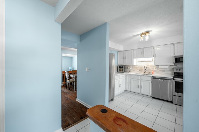 kitchen featuring sink, white cabinetry, light tile patterned floors, and stainless steel appliances