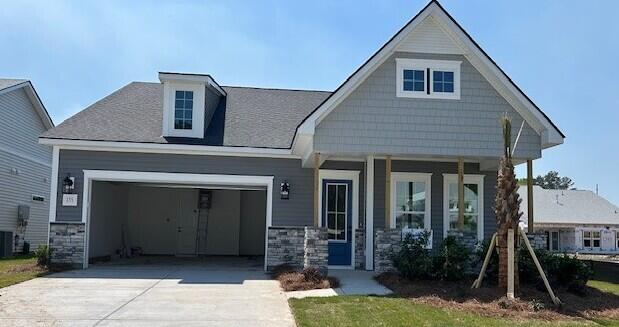 craftsman house featuring stone siding, a porch, a garage, and concrete driveway