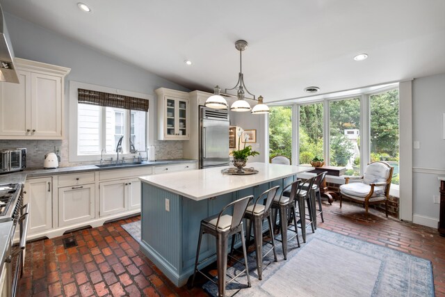 kitchen with pendant lighting, a kitchen island, high quality appliances, sink, and decorative backsplash