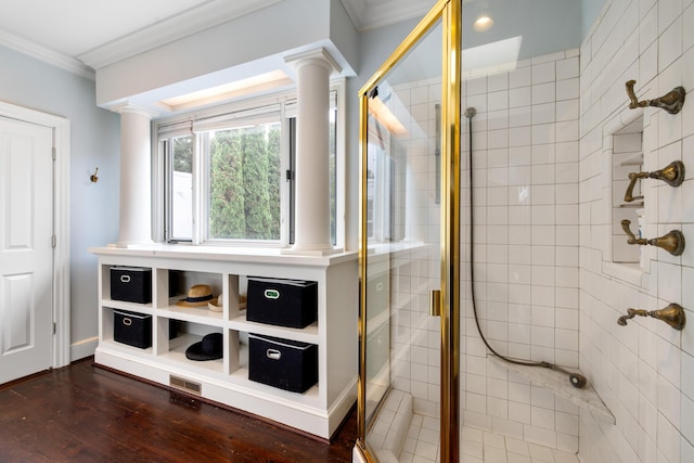 bathroom with decorative columns, crown molding, an enclosed shower, and wood-type flooring