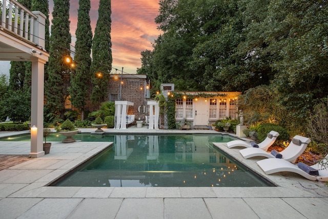 pool at dusk featuring a patio area