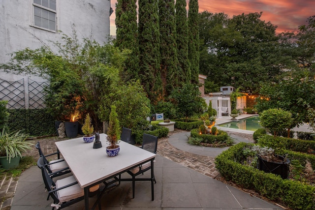 patio terrace at dusk featuring a fenced in pool