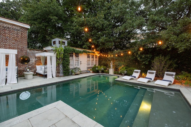 view of swimming pool with a patio and an outbuilding