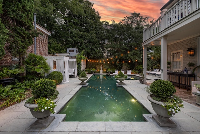 pool at dusk with a patio area