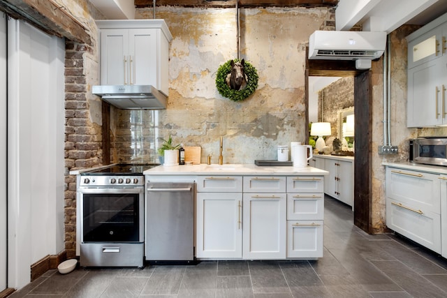 kitchen with appliances with stainless steel finishes, beam ceiling, white cabinetry, and an AC wall unit