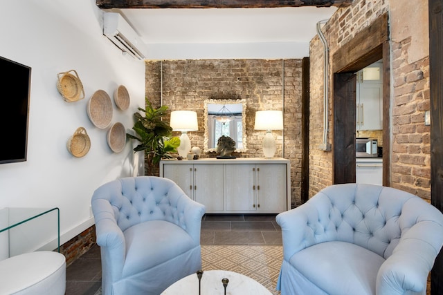 living area featuring dark tile patterned floors, a wall unit AC, beam ceiling, and brick wall