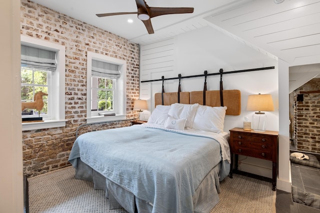 bedroom featuring brick wall, vaulted ceiling, and ceiling fan