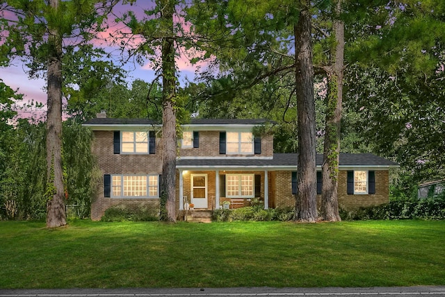 view of front facade with brick siding, a front lawn, and a porch