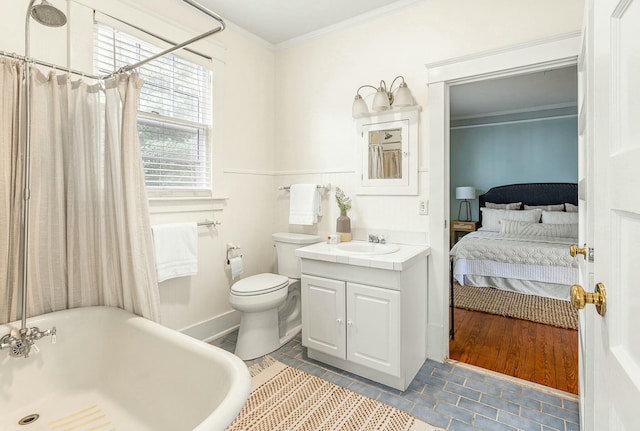 ensuite bathroom with toilet, ensuite bathroom, crown molding, a freestanding bath, and vanity