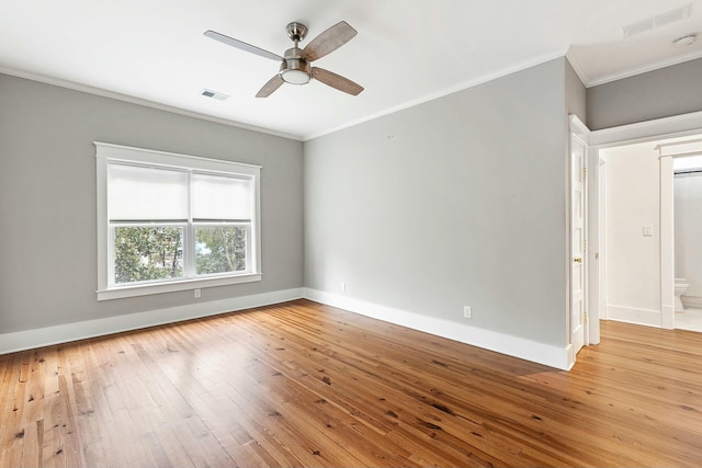 spare room featuring visible vents, crown molding, baseboards, and hardwood / wood-style flooring