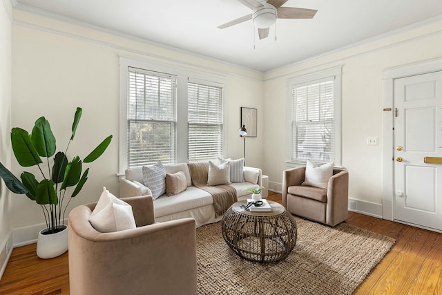 living room featuring ceiling fan, crown molding, baseboards, and wood finished floors