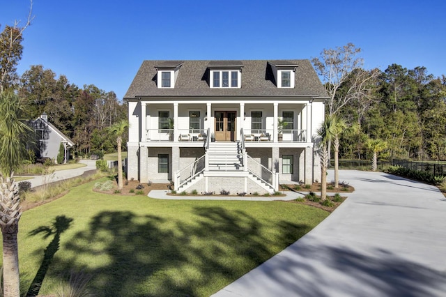 view of front of home featuring stairs, concrete driveway, a front yard, covered porch, and a shingled roof