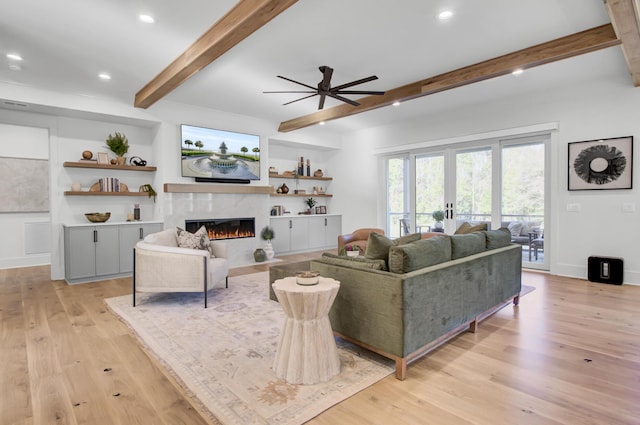 living room with a high end fireplace, ceiling fan, recessed lighting, beam ceiling, and light wood-type flooring