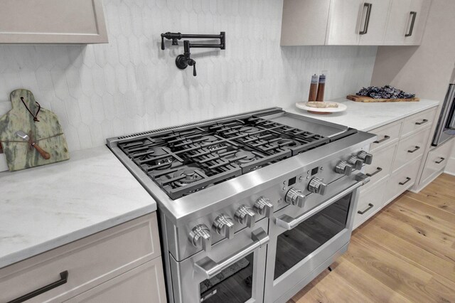 kitchen with light wood-style floors, white cabinets, backsplash, and double oven range