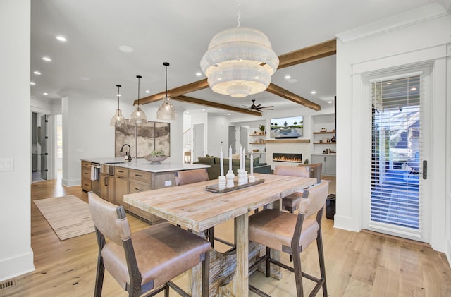 dining space featuring a warm lit fireplace, light wood finished floors, recessed lighting, a ceiling fan, and beam ceiling
