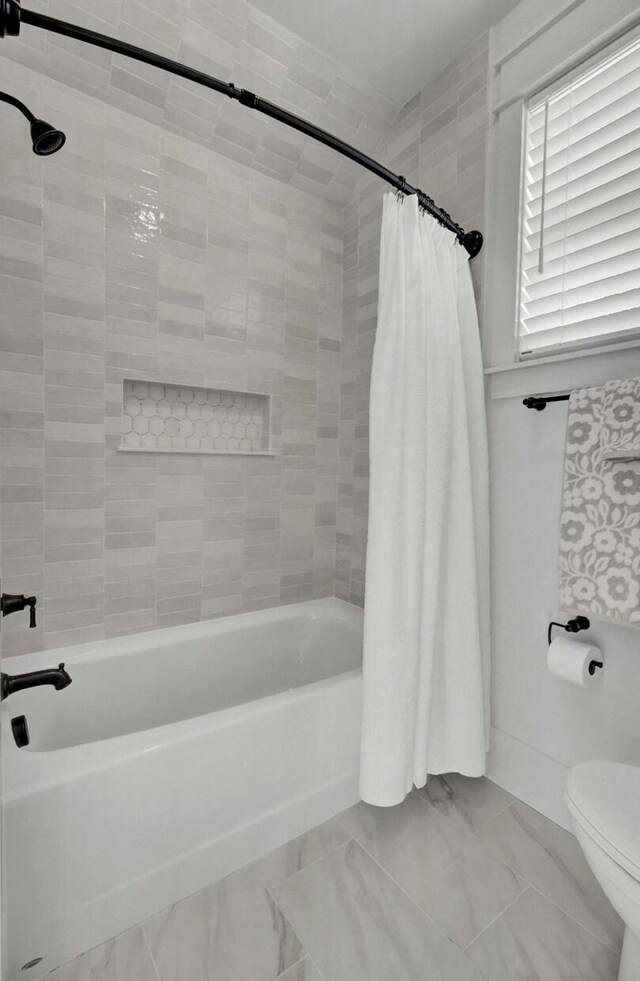 bathroom featuring shower / bath combination with curtain, marble finish floor, and toilet
