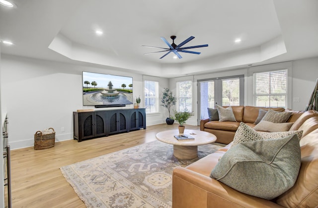 living area with baseboards, wood finished floors, recessed lighting, a ceiling fan, and a raised ceiling