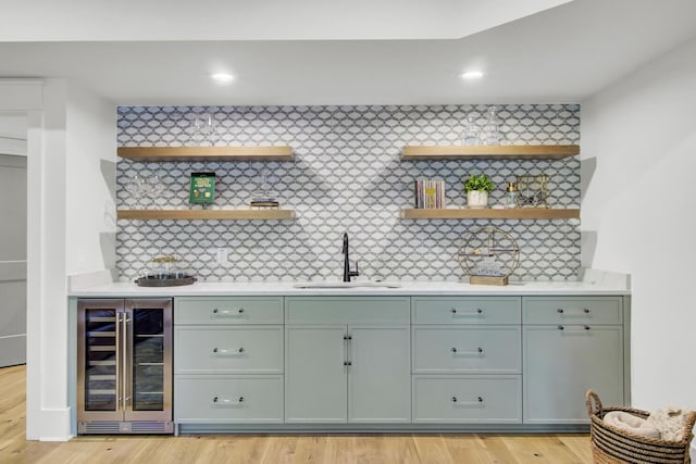 bar featuring indoor wet bar, a sink, wine cooler, and light wood-type flooring