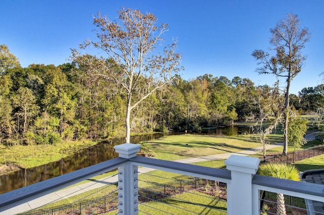 view of yard featuring a water view, fence, and a forest view