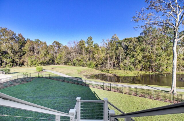 view of yard featuring a wooded view, a water view, and fence