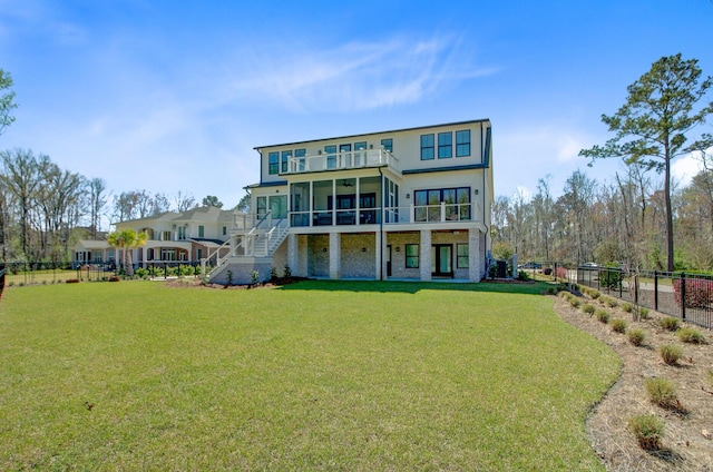 back of house featuring a sunroom, stairway, fence, a balcony, and a lawn