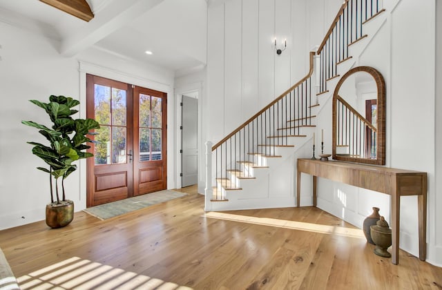 foyer entrance with hardwood / wood-style floors, stairs, french doors, and beam ceiling