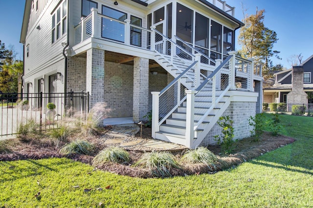 back of house with brick siding, a sunroom, stairway, and fence
