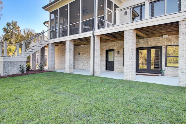 back of house with french doors, brick siding, a sunroom, a patio, and a lawn