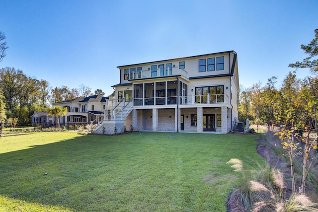 rear view of property with a sunroom, stairway, and a yard