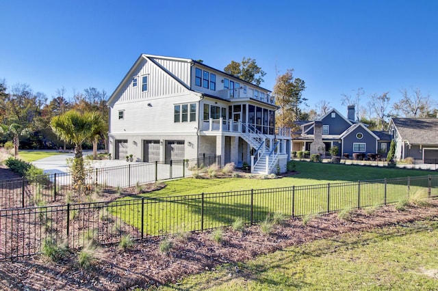 rear view of property featuring driveway, stairway, a sunroom, a lawn, and a garage