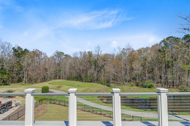 wooden deck with a wooded view, a yard, and fence
