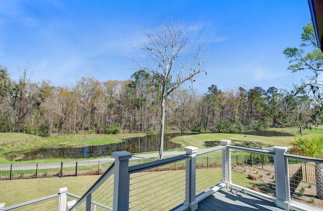 deck featuring a lawn, a water view, fence, and a wooded view