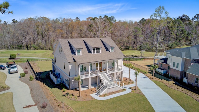exterior space with a front lawn, a forest view, a porch, and stairway