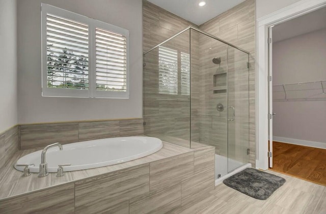 bathroom featuring plus walk in shower and hardwood / wood-style floors