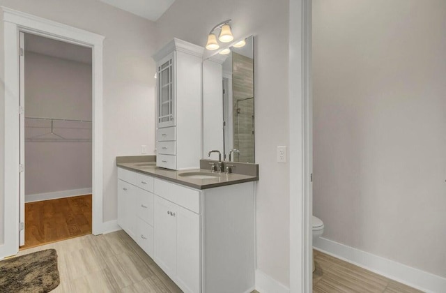 bathroom featuring walk in shower, vanity, hardwood / wood-style flooring, and toilet