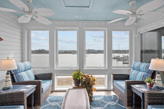 sunroom / solarium with a water view, ceiling fan, and a wealth of natural light