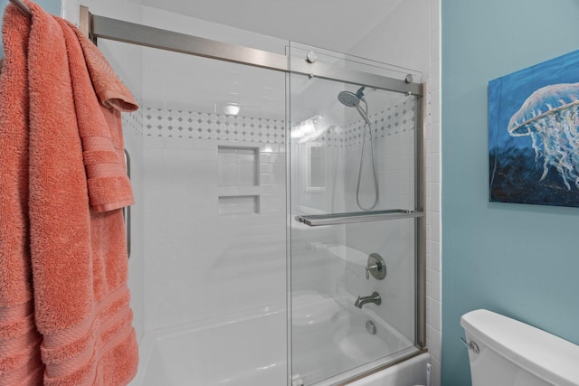 bathroom with toilet and combined bath / shower with glass door